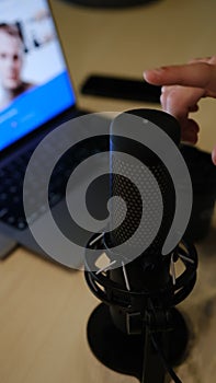 close up image of microphone in podcast studio. Mans bloger hand switch on microphone with led lights. Streamer podcast