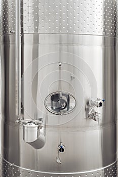 Close-up image of modern stainless steel barrel for wine fermentation at a winery. Wine industry.