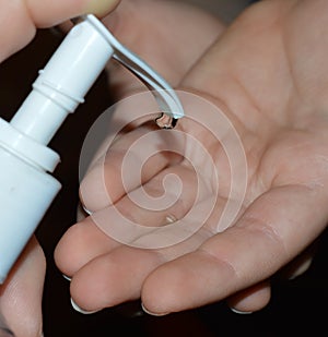 Close up image of mother helping child use hand sanitizer.