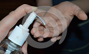 Close up image of mother helping child use hand sanitizer