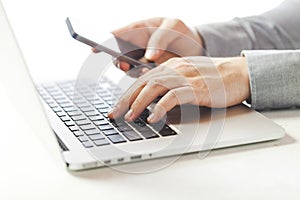 Close up image of multitasking business man using a laptop and mobile phone