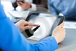 Close-up image of an office worker using a tablet to analyze statistical data.