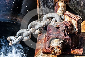 Close up image of old rusty bollard with chain on the pier