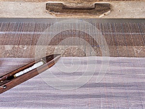 A close-up image of an old wooden shuttle on homemade threads and weaving loom, traditional textile production.