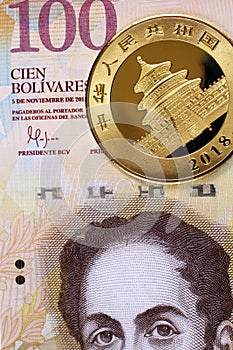 A Venezuelan 100 Bolivares bank note with a Chinese gold coin photo