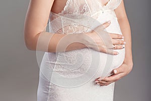 Close-up image of pregnant woman touching her belly with hands. Copy space