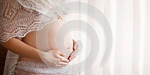 Close-up image of pregnant woman touching her belly with hands. Copy space