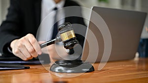 Close-up image of a professional male lawyer holding a judge gavel at his desk