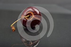 Close up of image of rotten red cherry fruit on reflective black