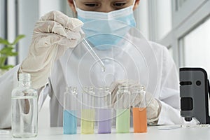 Close up image of schoolboy in protective clothers is ready for chemical experiments with liquids in different test tubes,