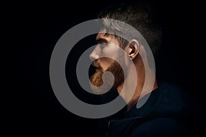 Close-up image of serious brutal bearded man on dark background