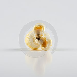 A close-up image of a single popped popcorn kernel. The kernel is light yellow with a