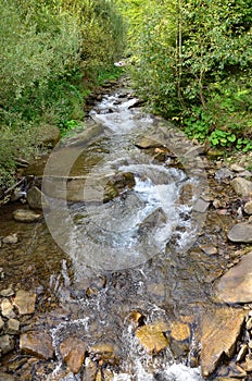 Close-up image of a small wild waterfall in the form of short streams of water between mountain stones