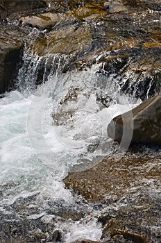 Close-up image of a small wild waterfall in the form of short streams of water between mountain stones