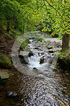 Close-up image of a small wild waterfall in the form of short streams of water between mountain stones