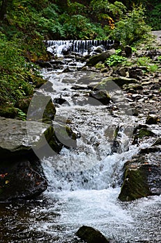 Close-up image of a small wild waterfall in the form of short streams of water between mountain stones