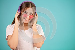 Close up image of smiling female DJ in blue headphones and rose sunglasses