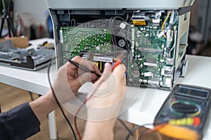 Close-up image of technician man hand measuring electrical voltage of computer mainboard by using digital multimeter.