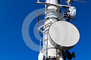 An close-up image of a telecommunications dish on a tower on a blue background