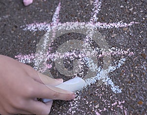A close up image of a tic-tac-toe chalk game. Child is drawing on the ground background