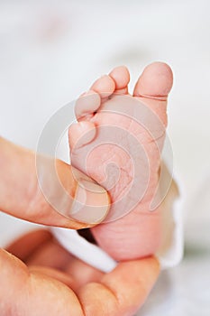 Image of tiny newborn baby feet holding by father