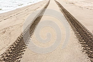 Close up image of tire tracks on the sand beach