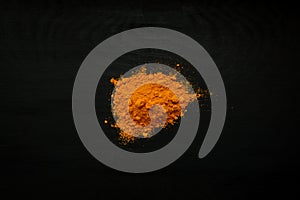 Close-up image of turmeric, curcuma powder on black wood background, view above