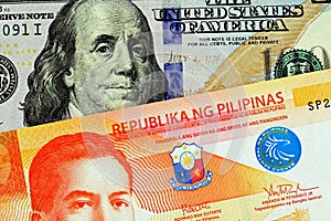 A close up image of a twenty Philippine peso with an American hundred dollar bill