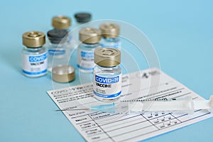 Close-up image of vaccine vial and syringe on CDC covid-19 vaccination record card.