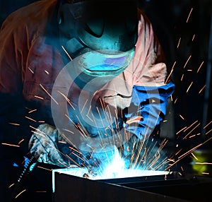 Close up image of a welder at work in full ppe, sparks fly as he welds. photo