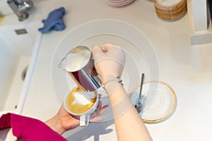 close-up image of white woman& x27;s hands pouring milk into a cappuccino coffee. copy space