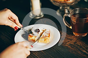 Close up image of a woman eating cherry pastries with fork and knif in cafe