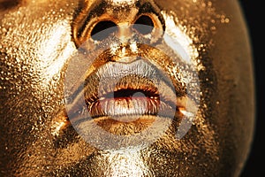 Close up image of woman face covered with gold