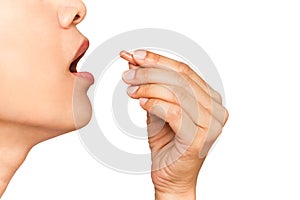 close up image of woman with her mouth open taking vitamin capsule isolate in white background.