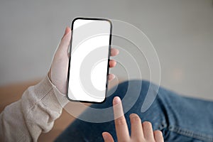 Close-up image of a woman sitting indoors and using her smartphone, touching on screen