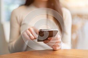 Close-up image of a woman sitting at a table indoors and using her smartphone. chat, message