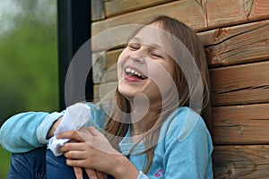 Close up image of young child laughing happily leaning on a wooden wall panel