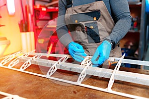 Close-up image of young male engineer or technician working on drone details in lab. Plane wing.