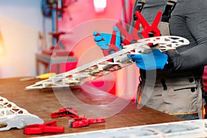 Close-up image of young male engineer or technician working on drone details in lab. Plane wing.