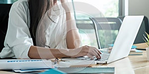 Close-up image of young professional female manager using laptop at her office, businesswoman working from home via