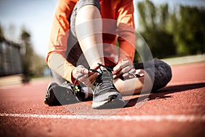 Close up image of young sport woman tying shoes.