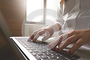 Close-up image of young woman hands typing and writing massages on laptop,working on cafe or home