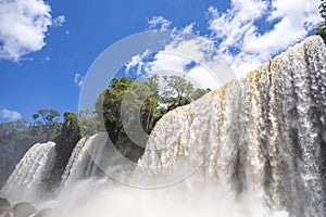 Close-up of impressive Iguazu Falls with blue sky and white clouds, Argentina