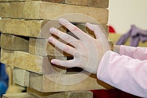 Close up Indian businesswoman building tower from wooden blocks in office, playing game