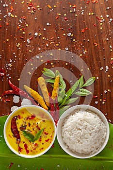 Close-up of Indian cooked rice with kadi or kadhi over the banana fresh green leaf. Garnished with curry-patta leaves, red chili photo