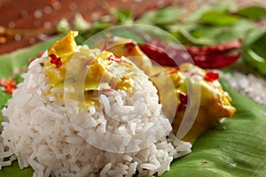 Close-up of Indian cooked rice with kadi or kadhi over the banana fresh green leaf. Garnished with curry-patta leaves, red chili