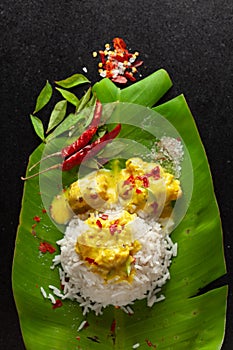 Close-up of Indian cooked rice with kadi or kadhi over the banana fresh green leaf. Garnished with curry-patta leaves, red chili