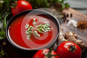 Close-up of Indian Homemade fresh and healthy tomato soup garnished with fresh coriander leaves and ingredients and herbs, served