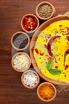 Close-up of Indian kadi or kadhi pakora with it basic ingredients. Garnished with green curry-patta leaves and red chili flacks. photo