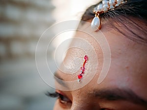 Close-up of Indian Mang Tikka decoration, TIKA on forehead of young woman